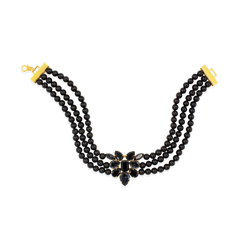 A three-strand black onyx beaded 24 carat gold plated Sildare Jewelry  choker necklace with a central black crystal floral cluster and gold-tone clasp ends, shown on a plain white background.