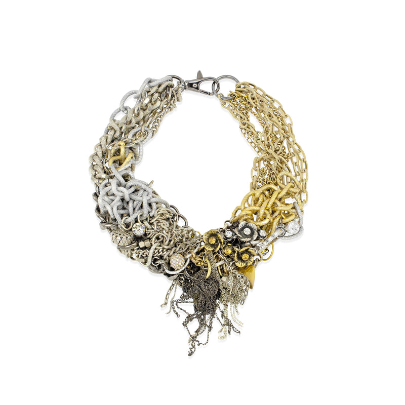 A multi-strand statement necklace featuring mixed metals including silver, gold, and bronze black chains, charms, and dangling elements, displayed on a clean white background.